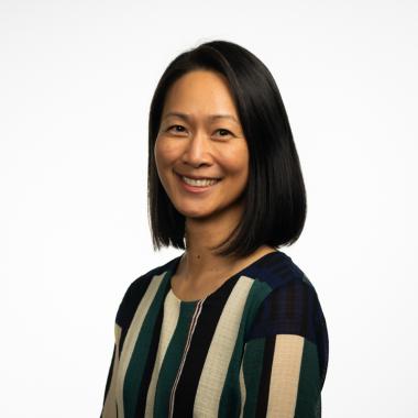 Headshot of Jane Duong, an Asian American woman with shoulder length black hair and a black, cream, and dark green vertical striped blouse.